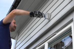 a person painting their home’s exterior